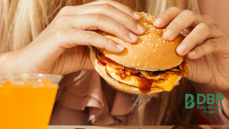 Person holding a burger as an example of saturated fat intake linked to high blood pressure